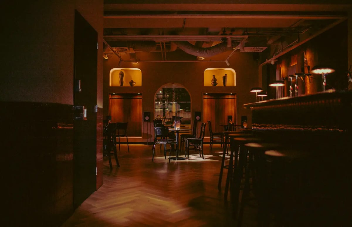 Warmly lit event space at Unit699 with bar seating and private tables, ready for business gatherings.
